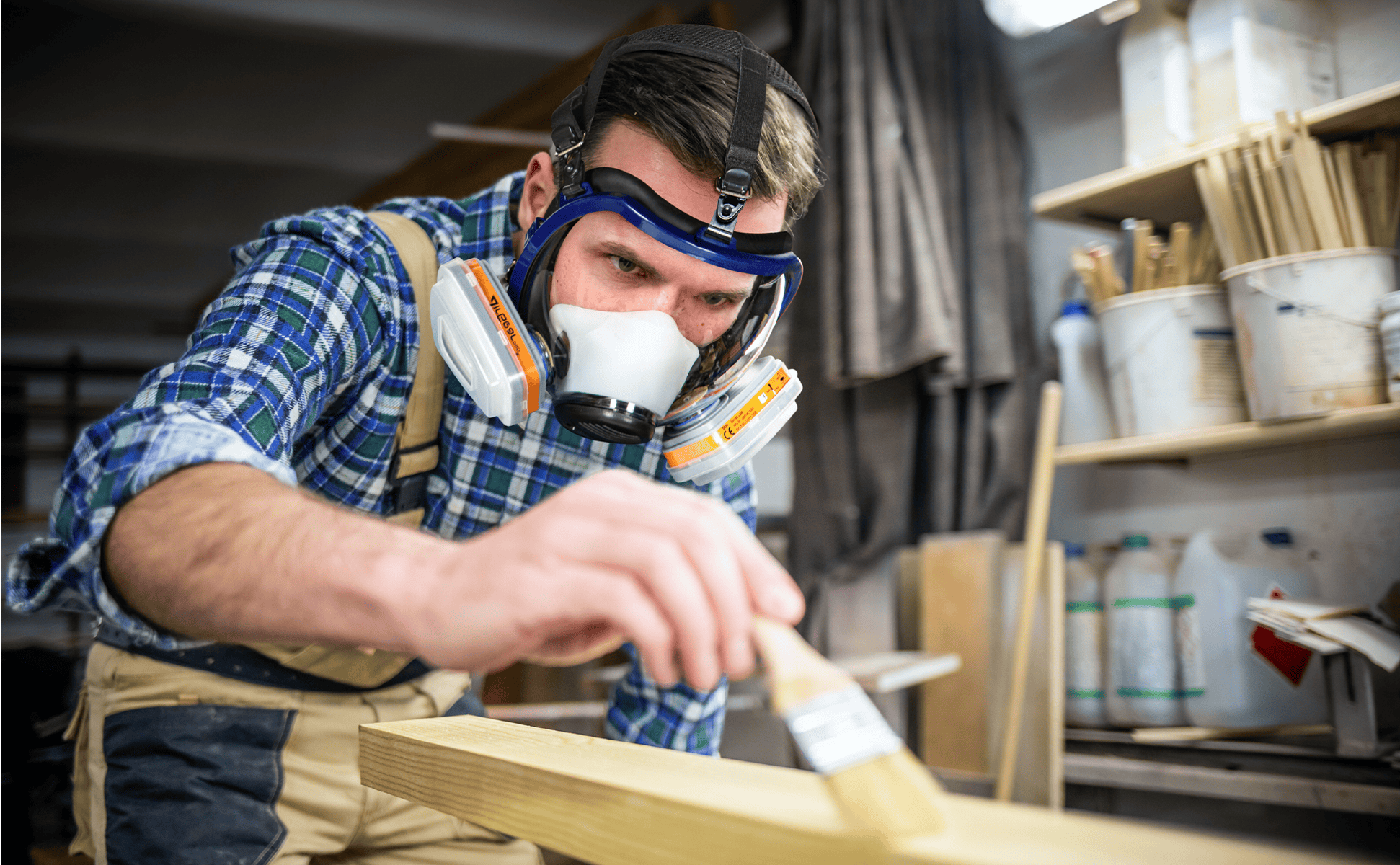 High-quality industrial worker sanding wooden plank in workshop with safety gear and robust tools for carpentry and woodworking.