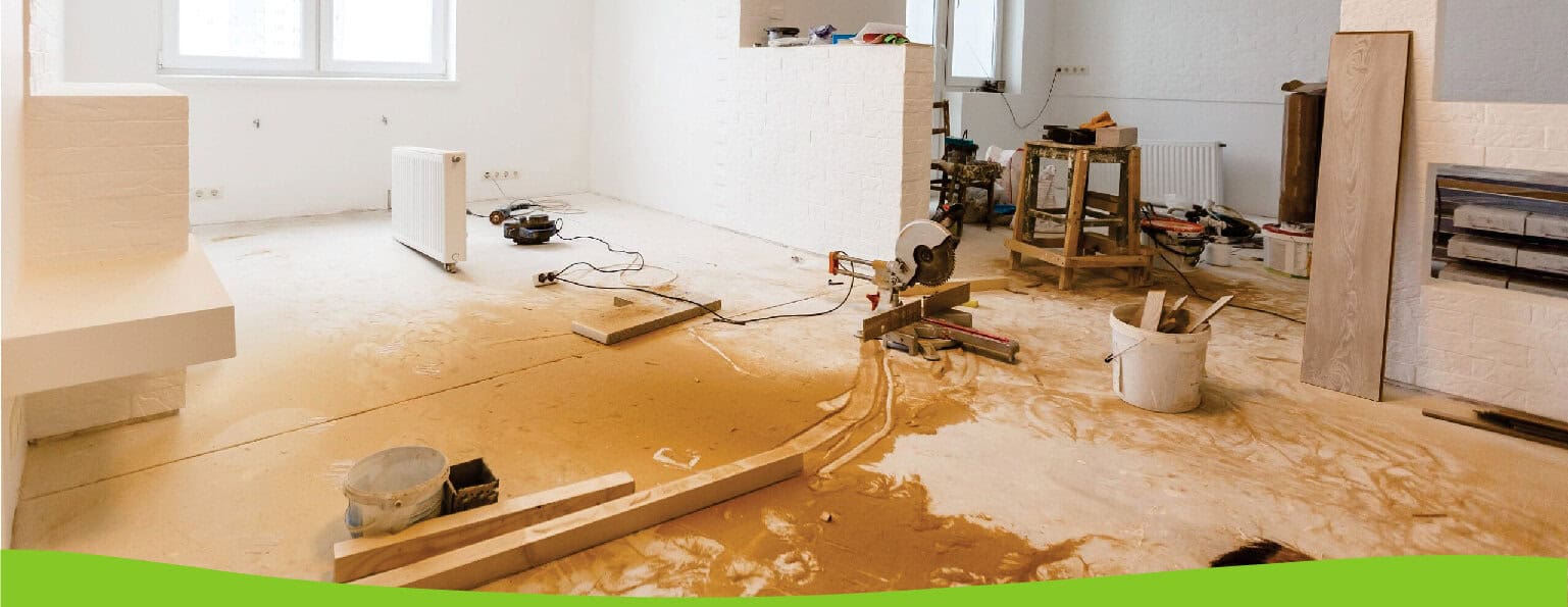 Cutting and installing wooden flooring in a modern living room under renovation with construction tools and materials present.