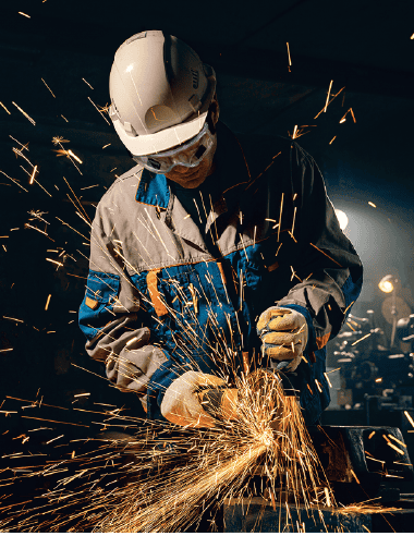 Welding worker wearing protective gear sparks flying in an industrial workshop, showcasing metal fabrication and welding safety equipment.